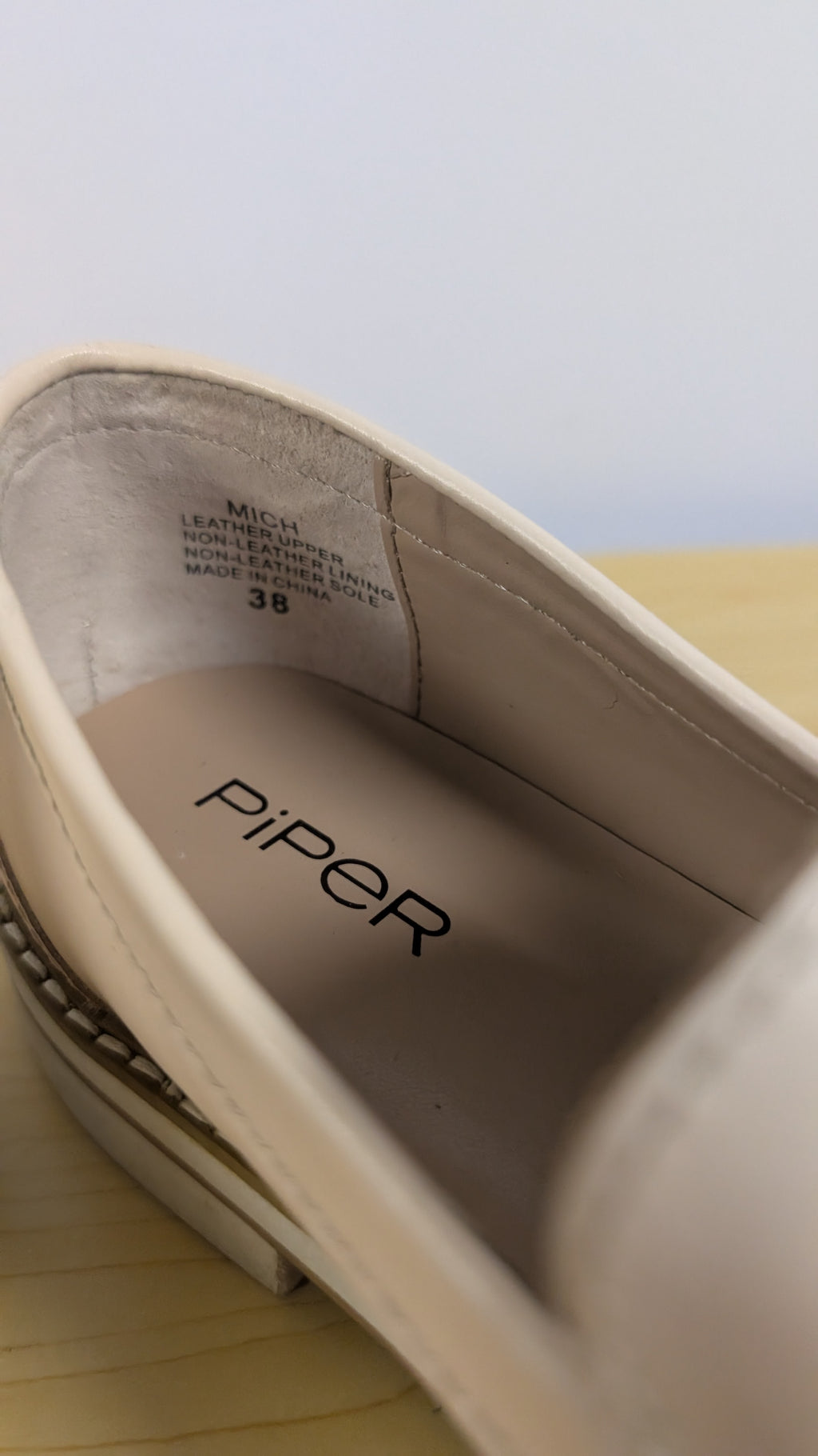 Close-up of a shoe with 'Piper' branding on a light background