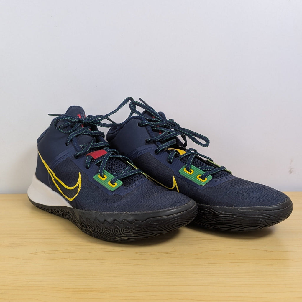 Pair of blue athletic shoes with a yellow logo on a wooden surface.