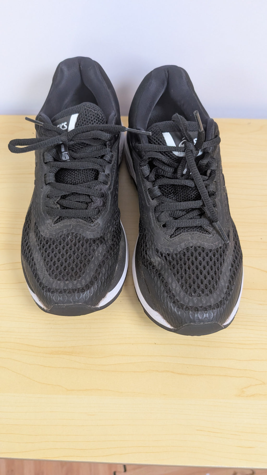 Pair of black athletic shoes on a wooden surface with a white background
