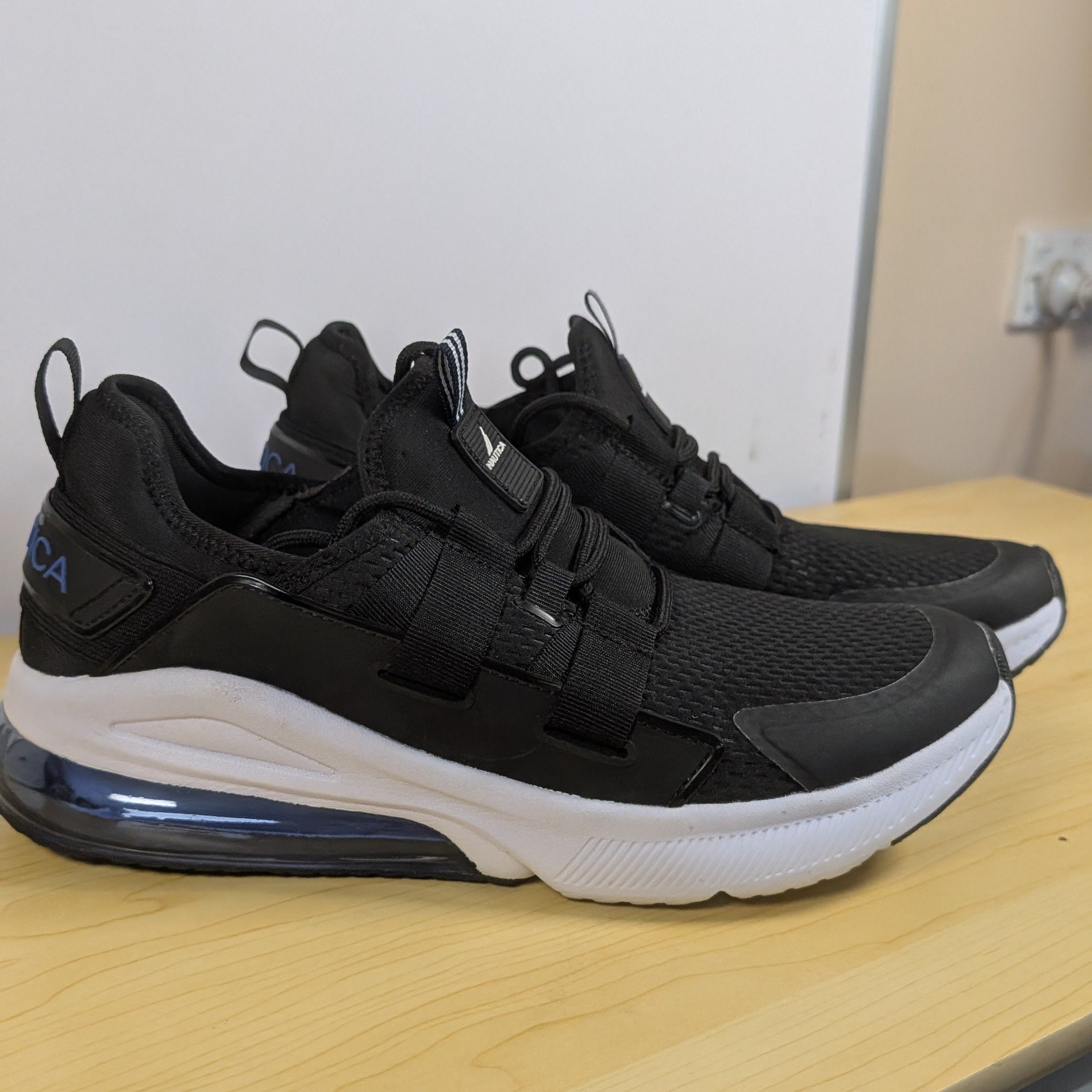 Black sneakers with white soles on a wooden surface