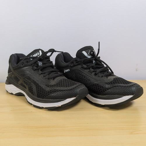 Black running shoes on a wooden surface with a white background